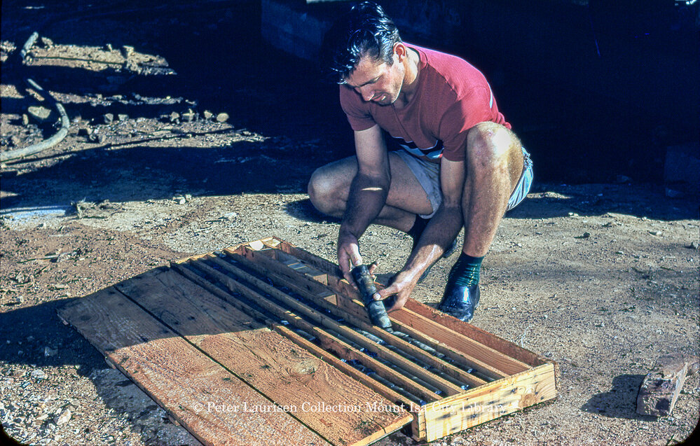 Worker placing drill core into diamond driller core box, Mount Isa Mines, c.1956