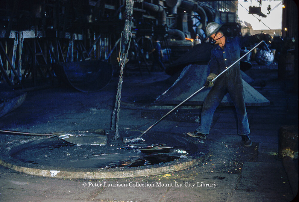 Stirring molten lead in drossing kettle at Lead Smelter, Mount Isa Mines, July 1956