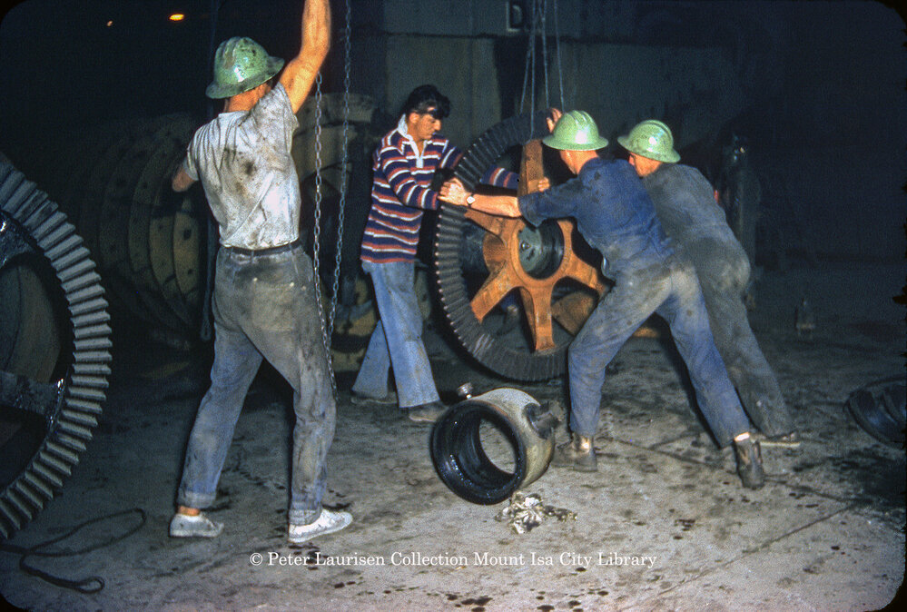 Workers lifting a gear wheel at Mill, Mount Isa Mines, c.1956