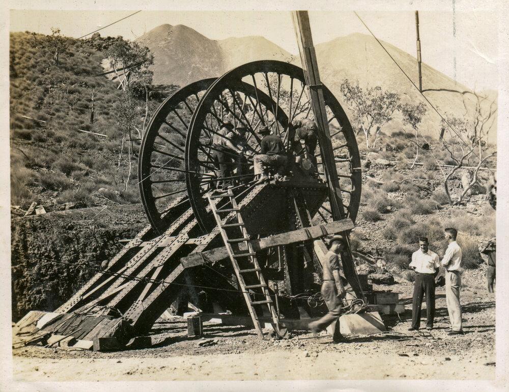 Workers installing sheave wheel over boreholes at No 2 ore shaft, Mount Isa Mines, c.1937