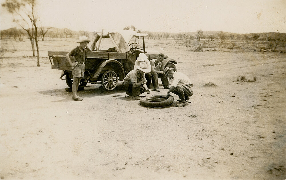 Group of men on shooting trip repairing a flat tyre