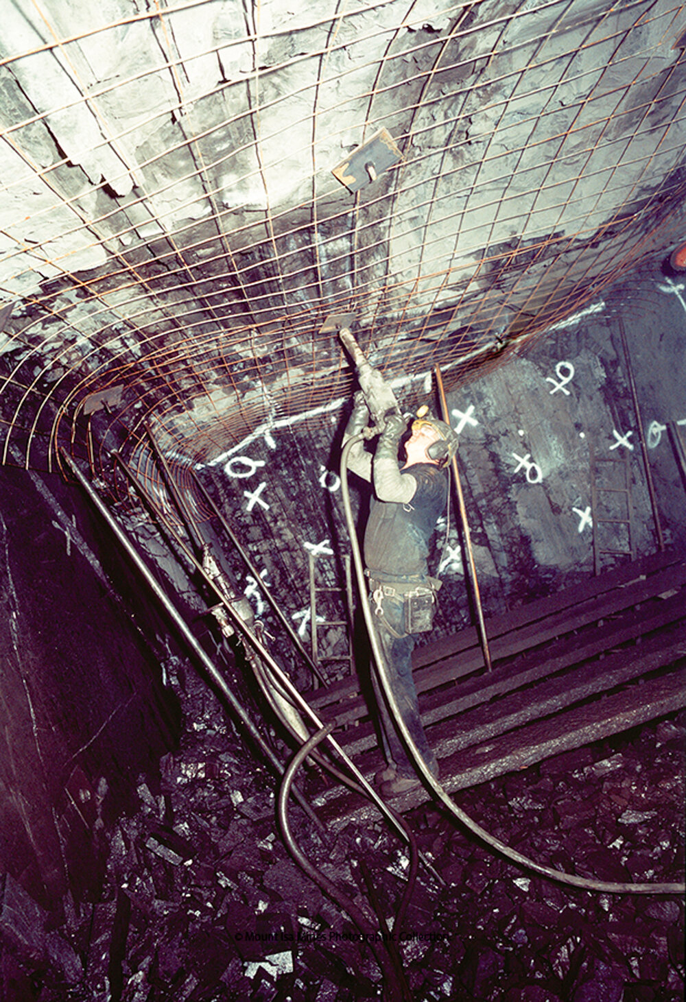 Tensioning bolts on mesh plate near face in copper mine, Mount Isa Mines, c.1986