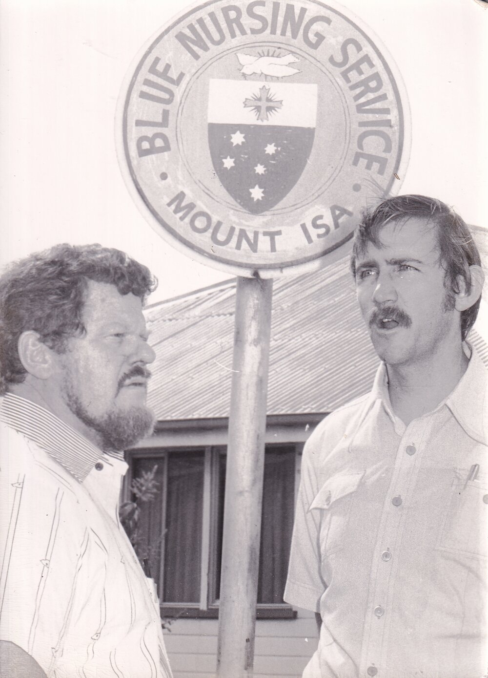 Two men standing outside the Blue Nursing Service headquarters