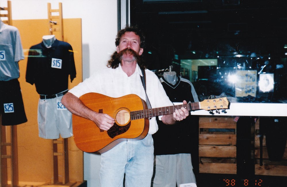 Mustached busker outside shop