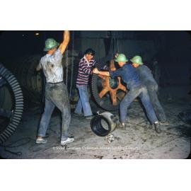Workers lifting a gear wheel at Mill, Mount Isa Mines, c.1956