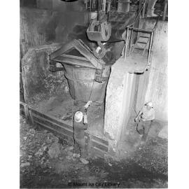 Crane chaser connecting crane hook to pot bridle at Copper Smelter, Mount Isa Mines, c.1956