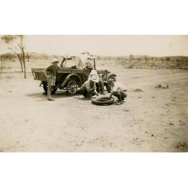 Group of men on shooting trip repairing a flat tyre