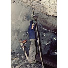 Underground worker bolting mesh plate to ground support in lead mine, Mount Isa Mines, c.1986