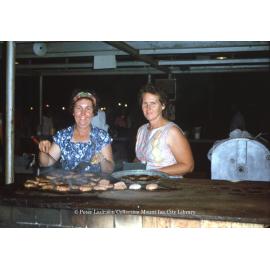 Mrs Freeman and friend cooking hamburgers, Mount Isa Exhibition, Spear Creek, May 1963