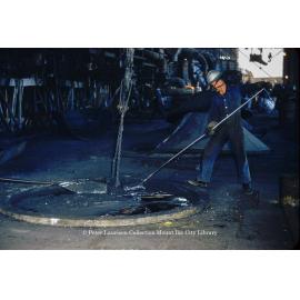 Stirring molten lead in drossing kettle at Lead Smelter, Mount Isa Mines, July 1956